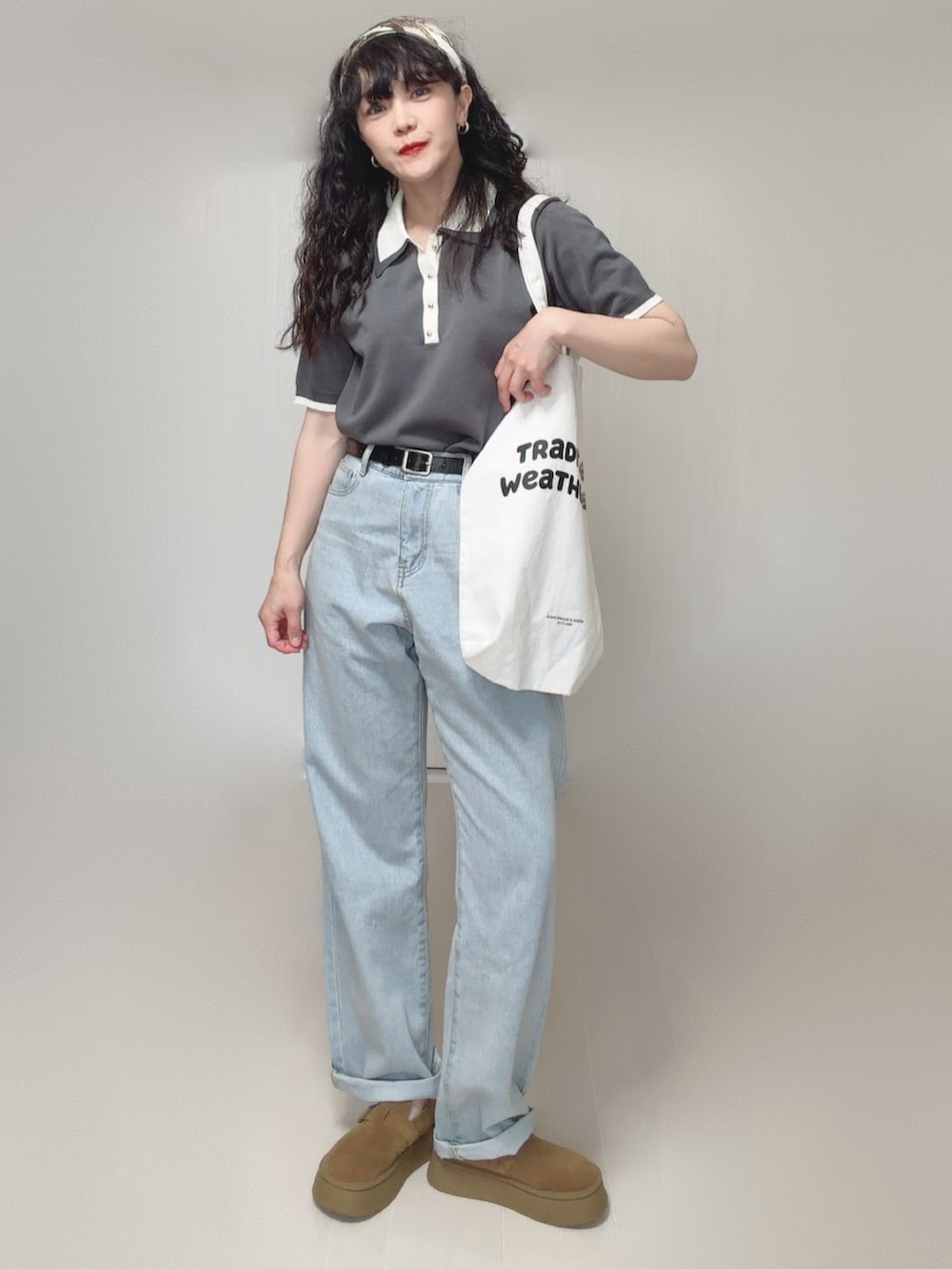 グレー系のポロシャツ、ブルー系のデニムパンツ、ホワイト系のトートバッグを着用したレディースの夏コーディネートの4枚目の写真