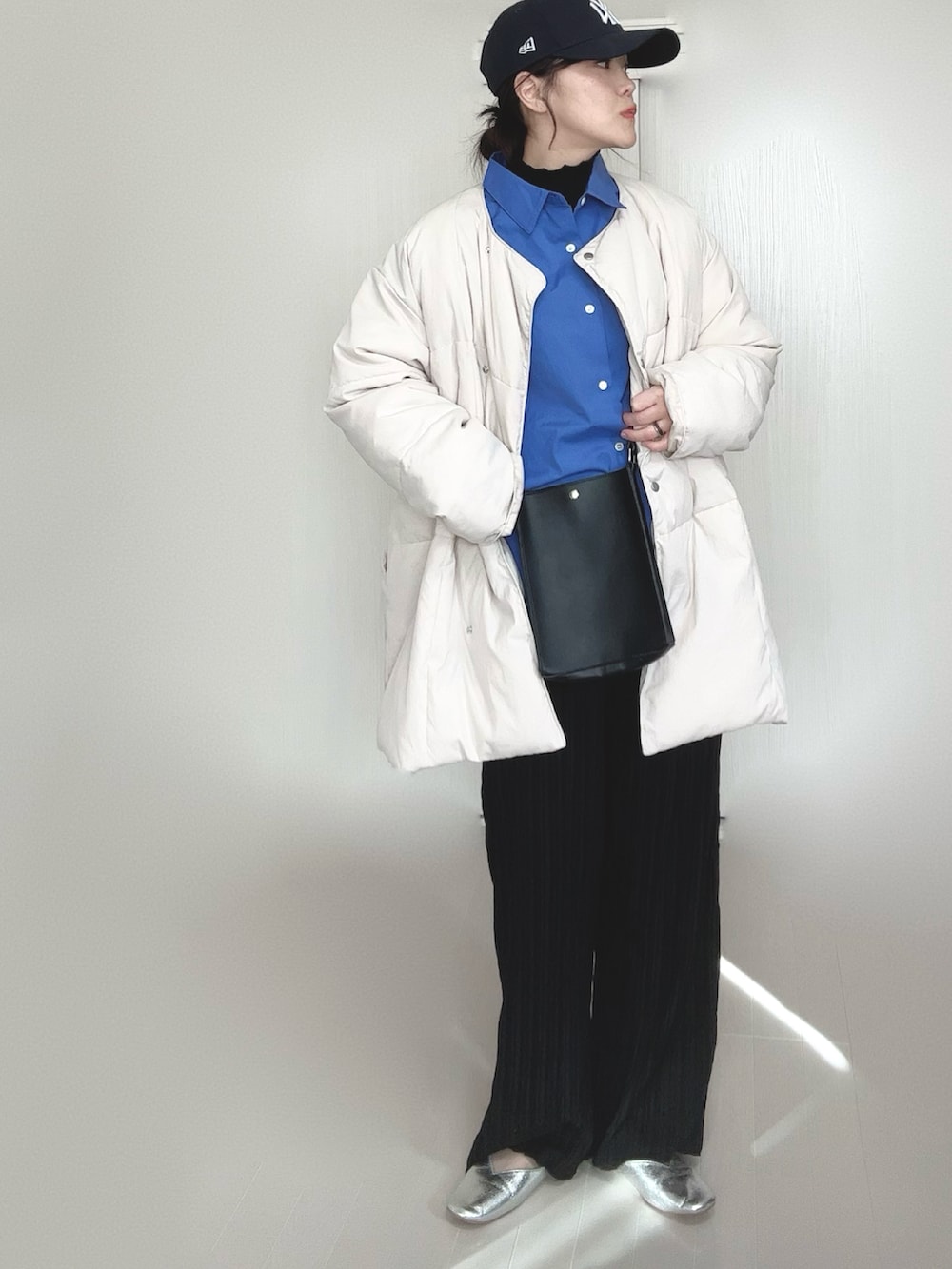 ホワイト系のダウンジャケット/コート、ブルー系のシャツ/ブラウス、ブラック系のショルダーバッグを着用したレディースの冬コーディネートの2枚目の写真