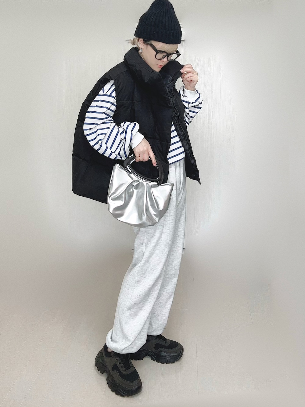 ブラック系のダウンベスト、ブラック系のスニーカー、オレンジ系のニットキャップ/ビーニーを着用したレディースの春コーディネートの4枚目の写真