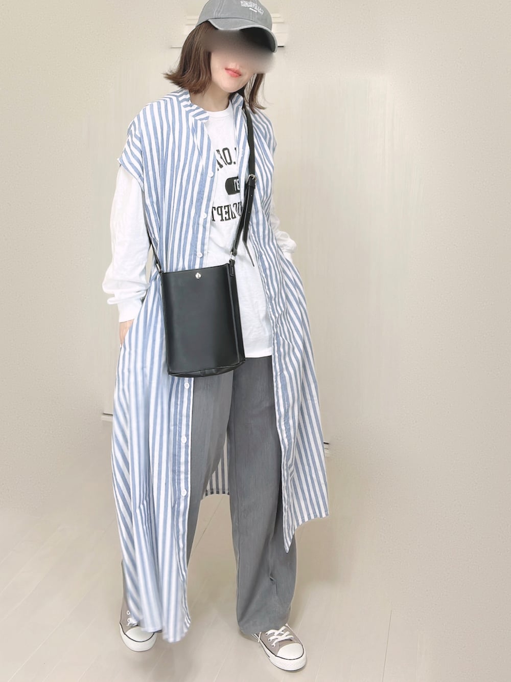 ブルー系のシャツワンピース、ホワイト系のTシャツ/カットソー、ブラック系のショルダーバッグを着用したレディースの春コーディネートの4枚目の写真