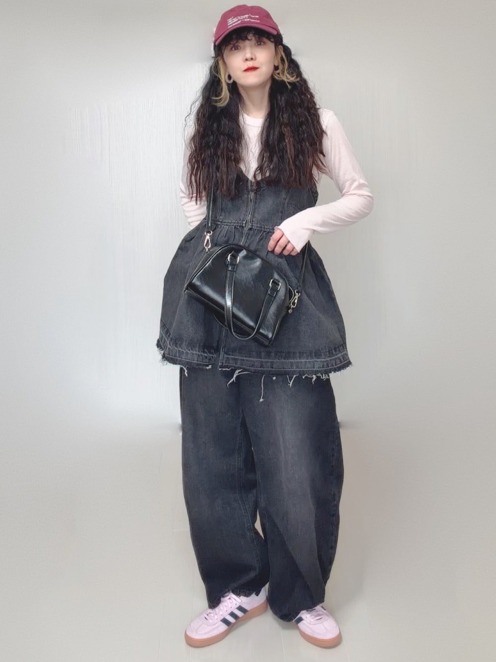 ブラック系のデニムパンツ、ブラック系のボストンバッグ、ピンク系のスニーカーを着用したレディースの春コーディネートの3枚目の写真