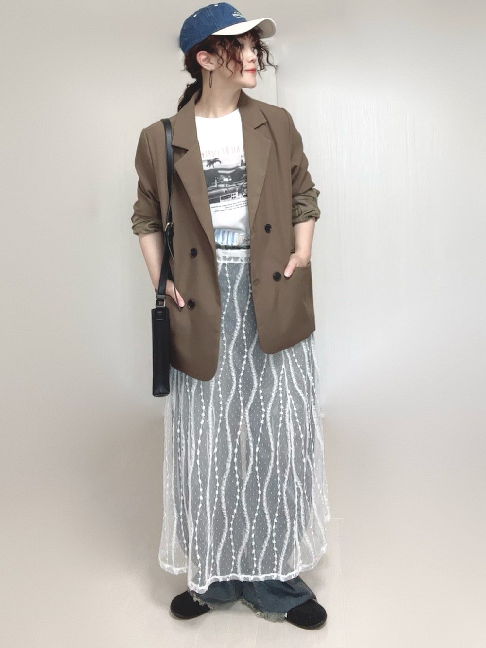 ブラウン系のテーラードジャケット、ブルー系のデニムパンツ、ホワイト系のスカートを着用したレディースの夏コーディネートの3枚目の写真