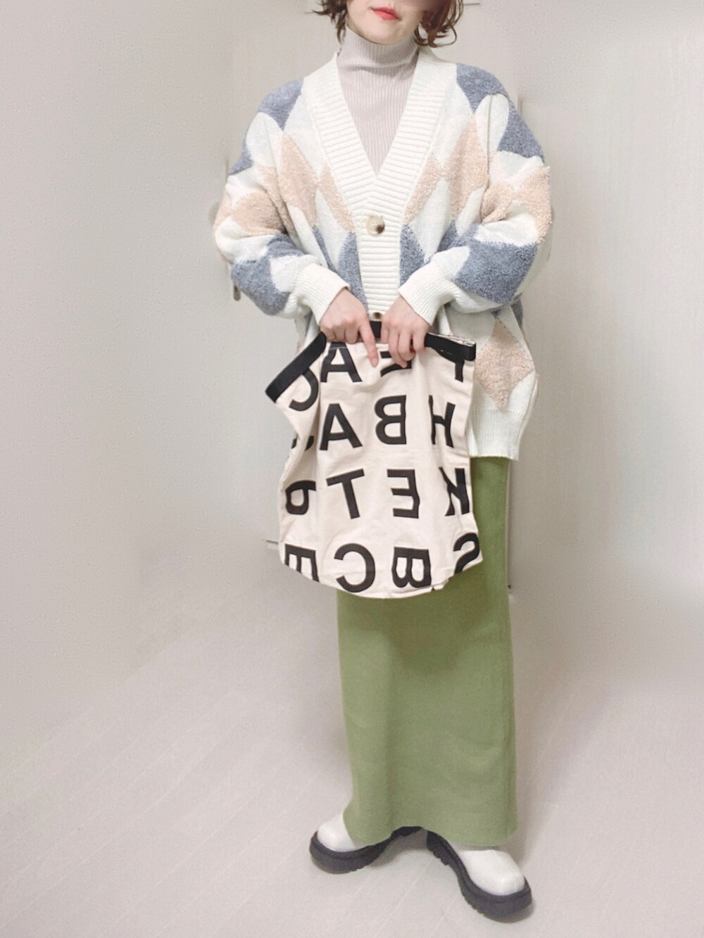 グリーン系のスカート、ホワイト系のブーツ、ホワイト系のトートバッグを着用したレディースの冬コーディネートの4枚目の写真