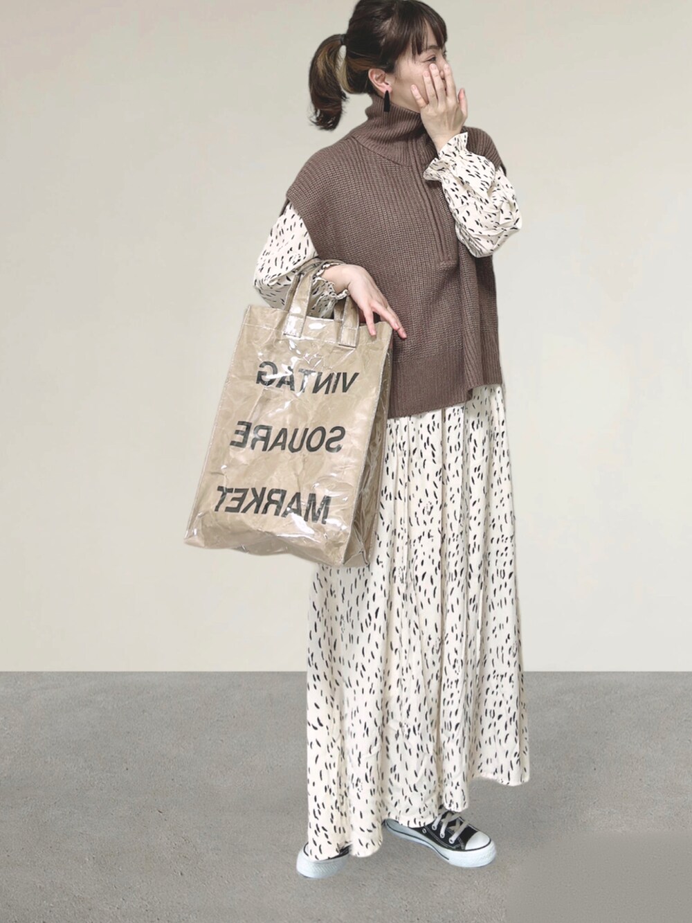 ブラウン系のベスト、ホワイト系のワンピース、グリーン系のトートバッグを着用したレディースの秋コーディネートの5枚目の写真