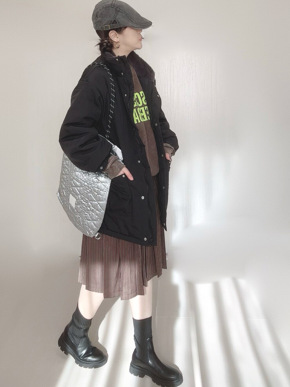 ブラック系のブルゾン、ブラウン系のスウェット、シルバー系のトートバッグを着用したレディースの冬コーディネートの4枚目の写真