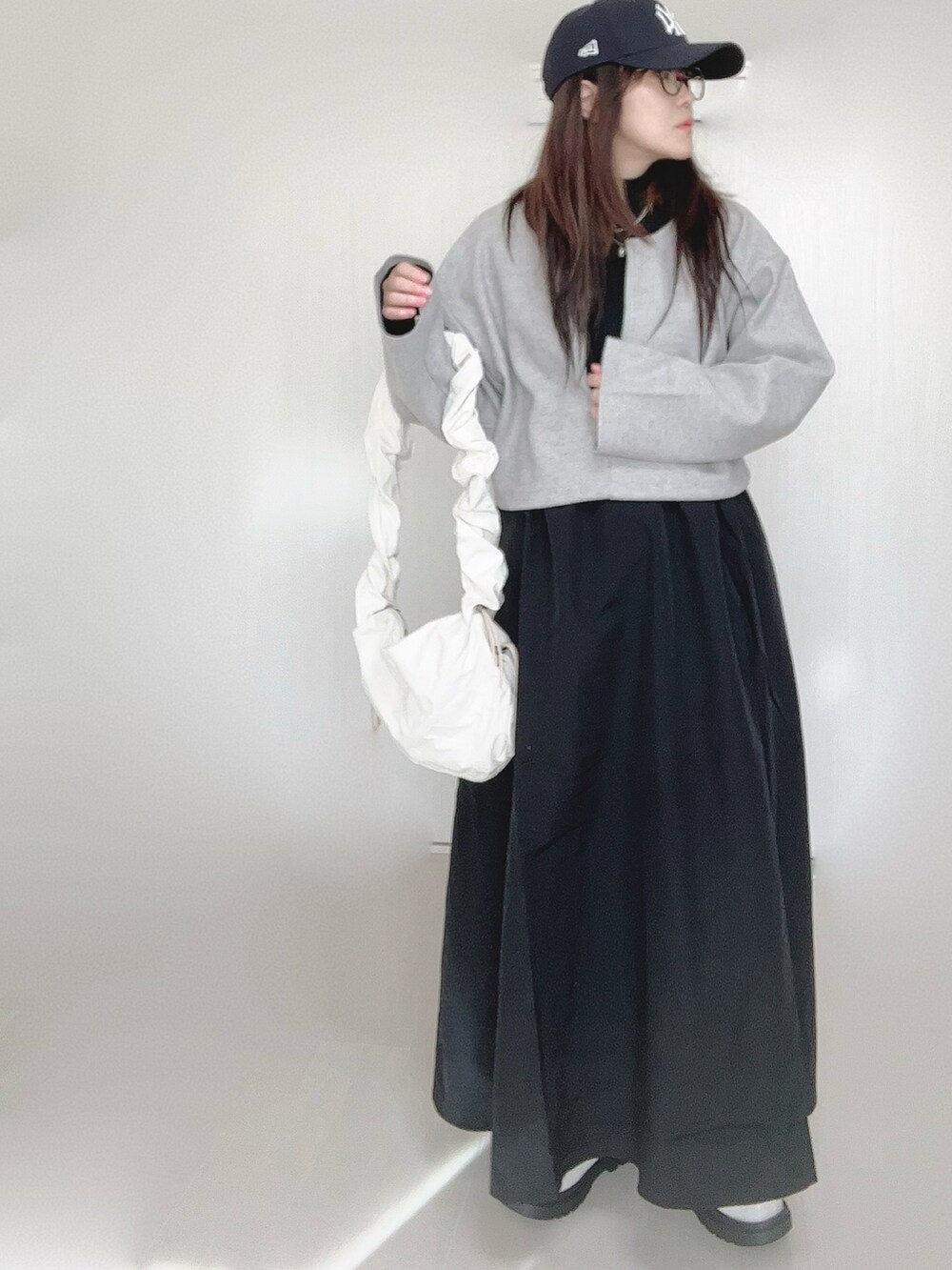 グレー系のワンピース、ホワイト系のショルダーバッグ、ホワイト系のブーツを着用したレディースの秋コーディネートの3枚目の写真