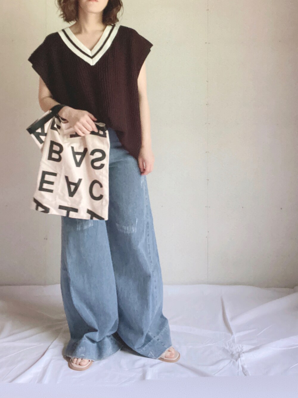 ブラック系のベスト、ホワイト系のトートバッグ、ホワイト系のサンダルを着用したレディースの夏コーディネートの4枚目の写真