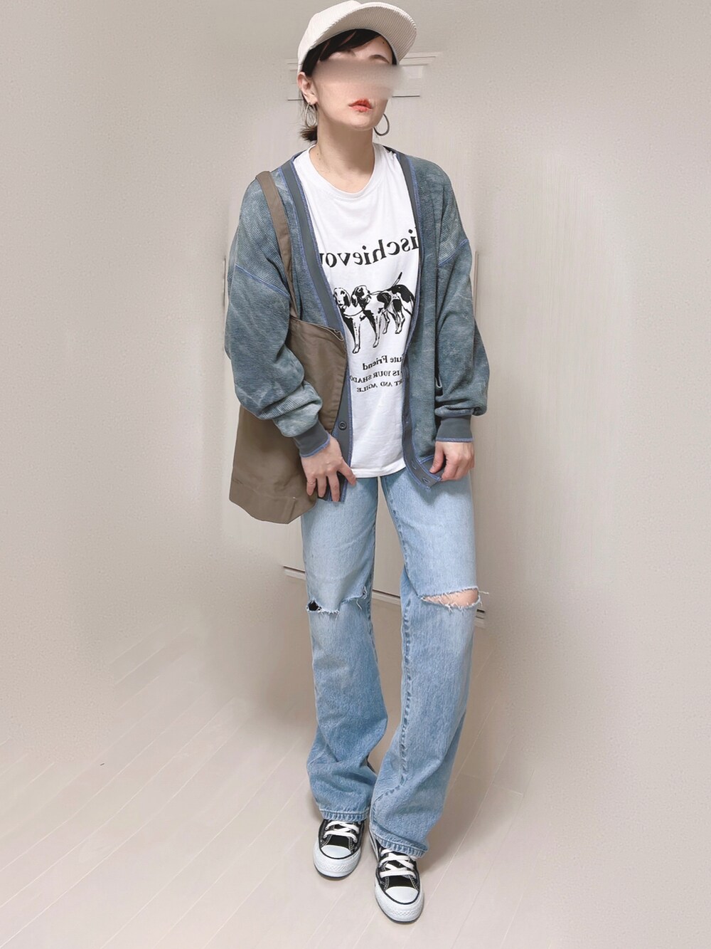 ブルー系のデニムパンツ、ブラック系のカーディガン/ボレロ、ブラウン系のトートバッグを着用したレディースの春コーディネートの2枚目の写真