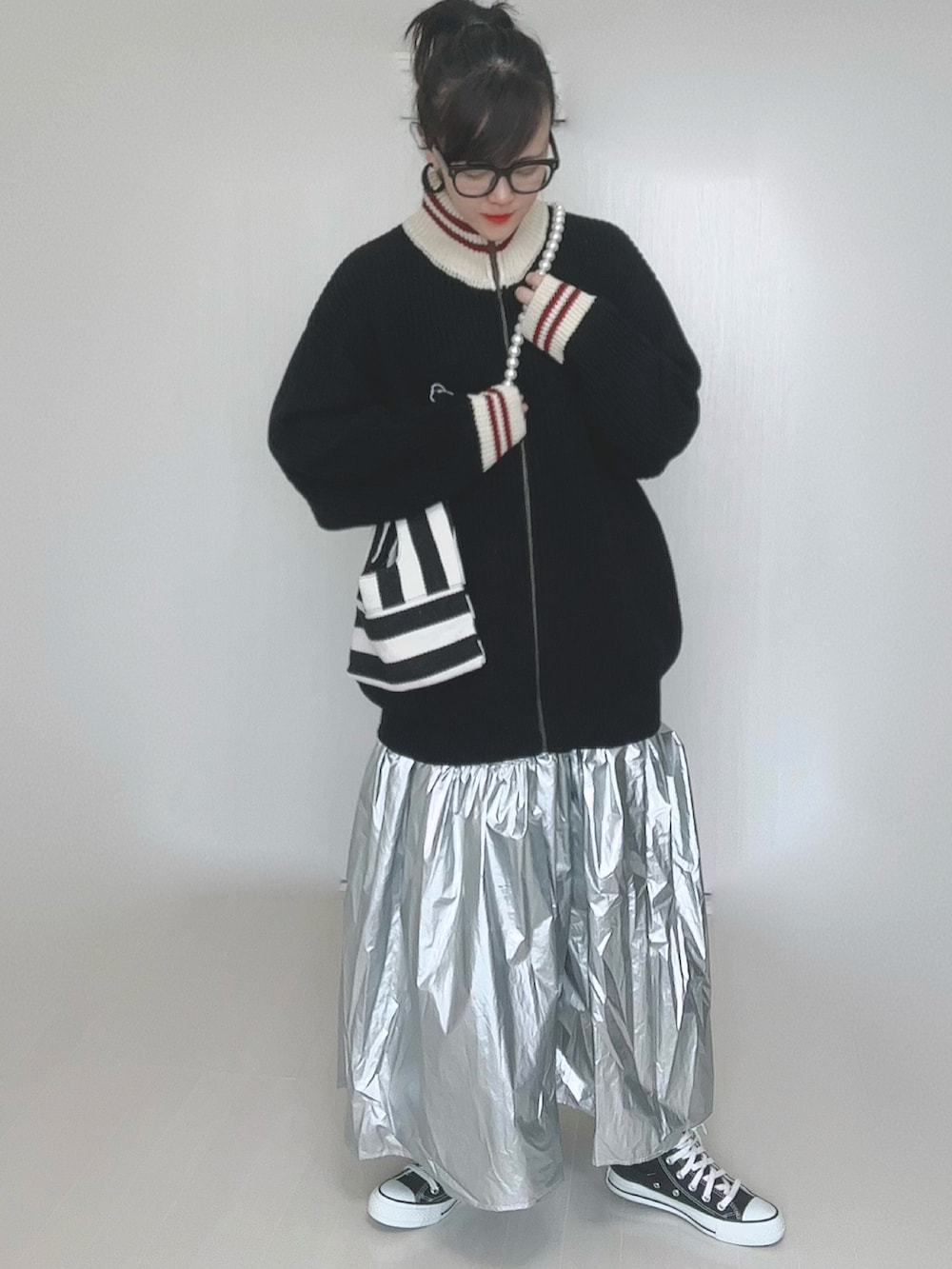 ブラック系のニット/セーター、ホワイト系のショルダーバッグ、シルバー系のスカートを着用したレディースの冬コーディネートの3枚目の写真