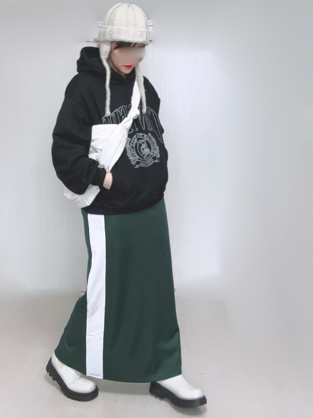 ブラック系のパーカー、ホワイト系のショルダーバッグ、グリーン系のスカートを着用したレディースの冬コーディネートの4枚目の写真