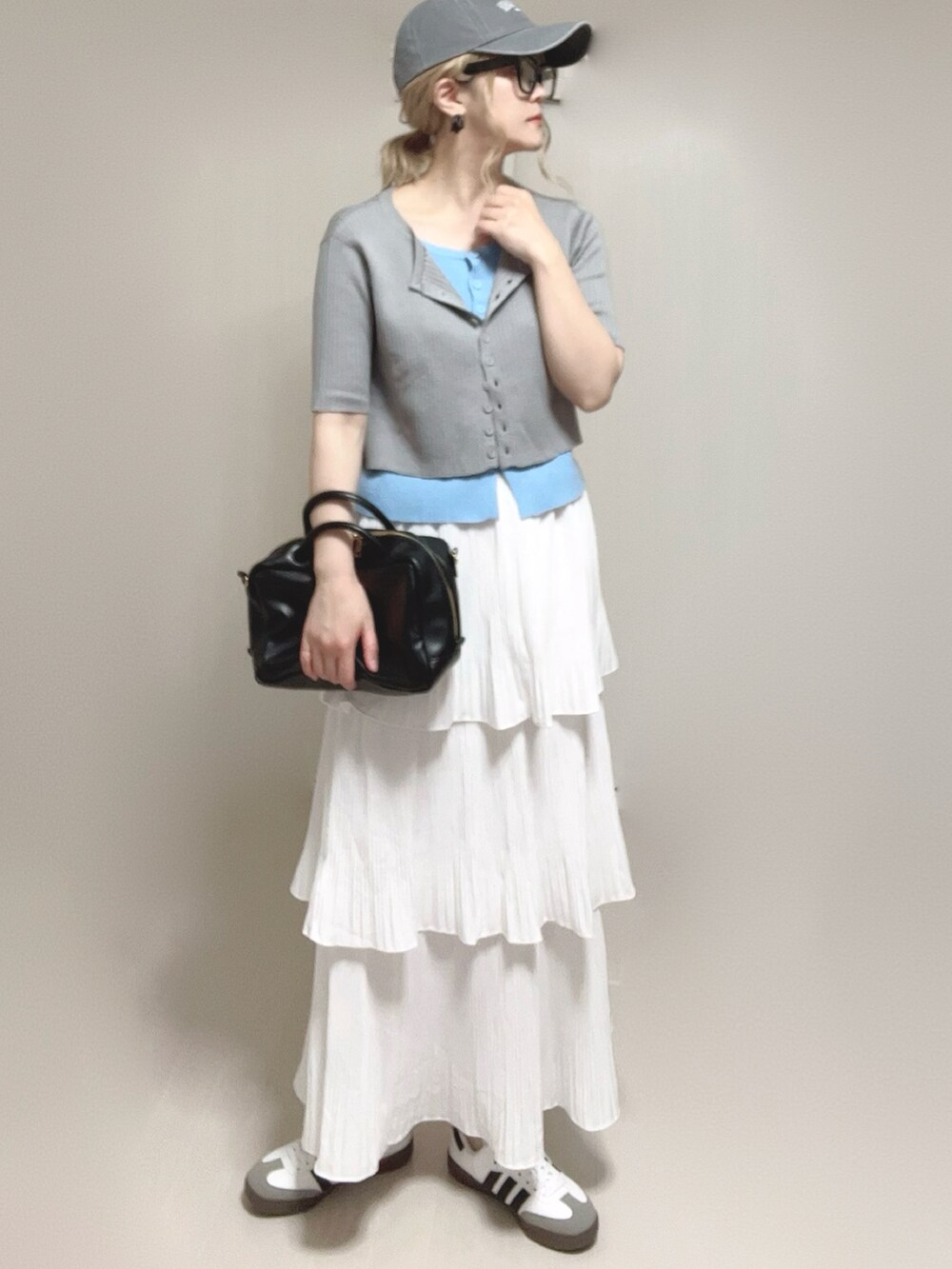 グレー系のニット/セーター、ブラック系のボストンバッグ、ホワイト系のスカートを着用したレディースの夏コーディネートの4枚目の写真