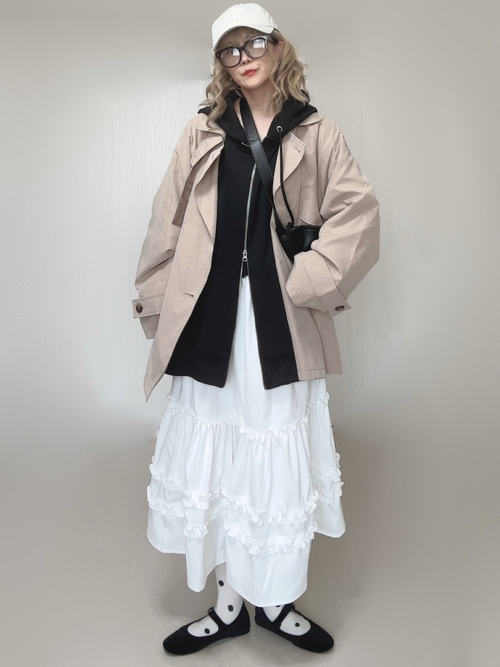 ブラック系のパーカー、ホワイト系のスカート、ベージュ系のトレンチコートを着用したレディースの春コーディネートの4枚目の写真