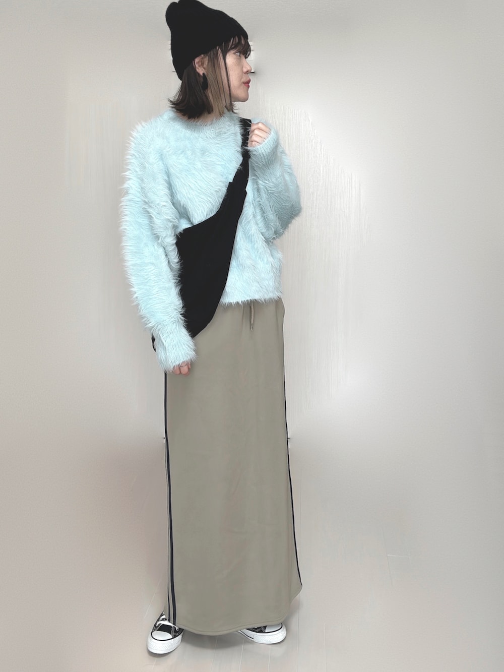 ブルー系のニット/セーター、ブルー系のスカート、ブラック系のスニーカーを着用したレディースの秋コーディネートの3枚目の写真