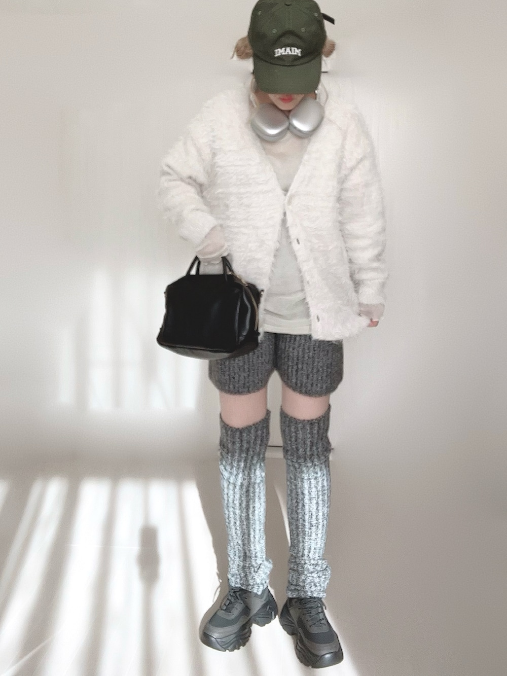 ホワイト系のカーディガン/ボレロ、グレー系のその他パンツ、ブラック系のボストンバッグを着用したレディースの冬コーディネートの4枚目の写真