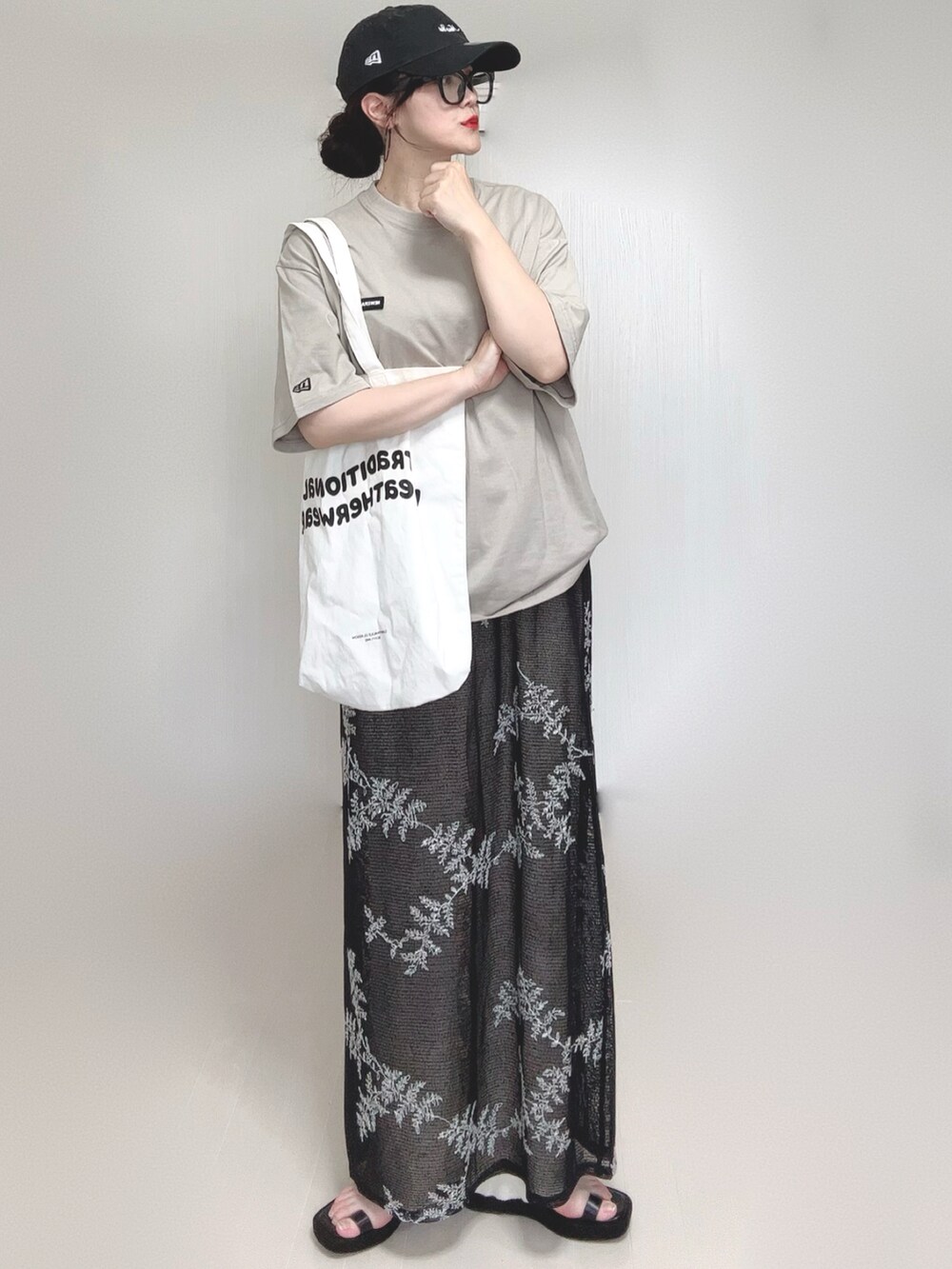 ブラック系のワンピース、ブラック系のサンダル、ベージュ系のTシャツ/カットソーを着用したレディースの夏コーディネートの4枚目の写真