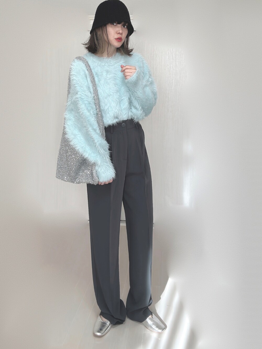 ブルー系のニット/セーター、グレー系のスラックス、シルバー系のパンプスを着用したレディースの秋コーディネートの3枚目の写真