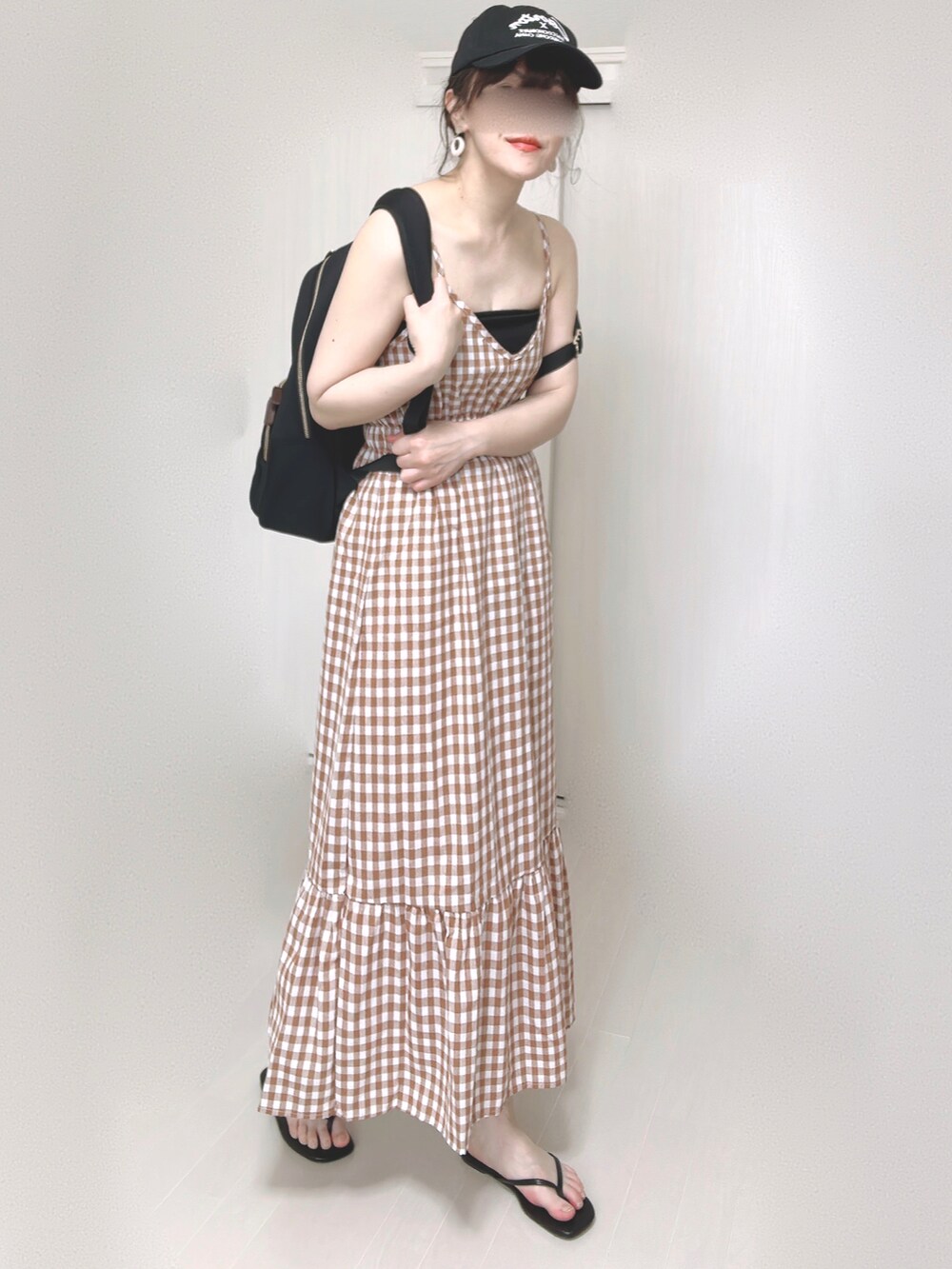 ブラック系のバックパック/リュック、オレンジ系のワンピース、ブラック系のサンダルを着用したレディースの夏コーディネートの4枚目の写真