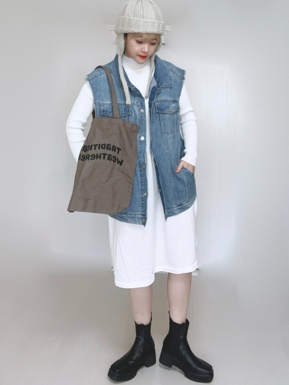 ホワイト系のワンピース、ブルー系のベスト、ブラウン系のトートバッグを着用したレディースの冬コーディネートの4枚目の写真