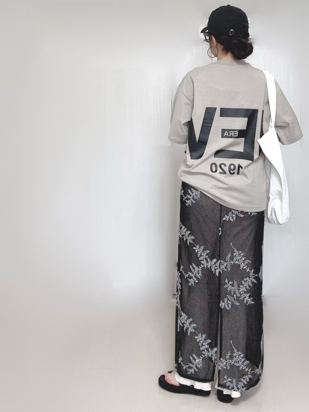 ブラック系のワンピース、ブラック系のサンダル、ベージュ系のTシャツ/カットソーを着用したレディースの夏コーディネートの5枚目の写真