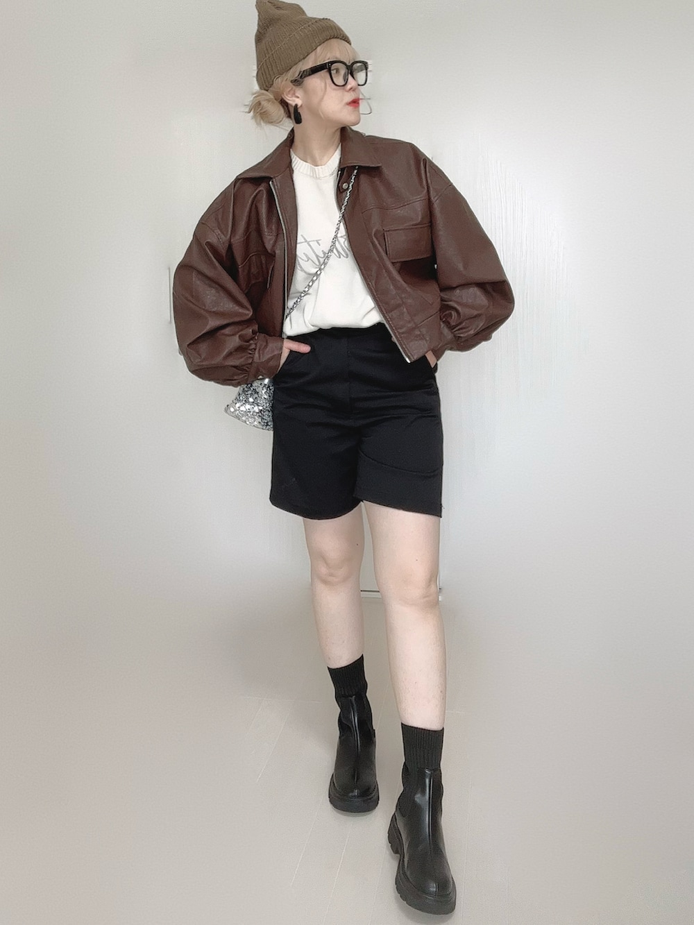 ブラウン系のブルゾン、ホワイト系のニット/セーター、ブラック系のブーツを着用したレディースの秋コーディネートの5枚目の写真