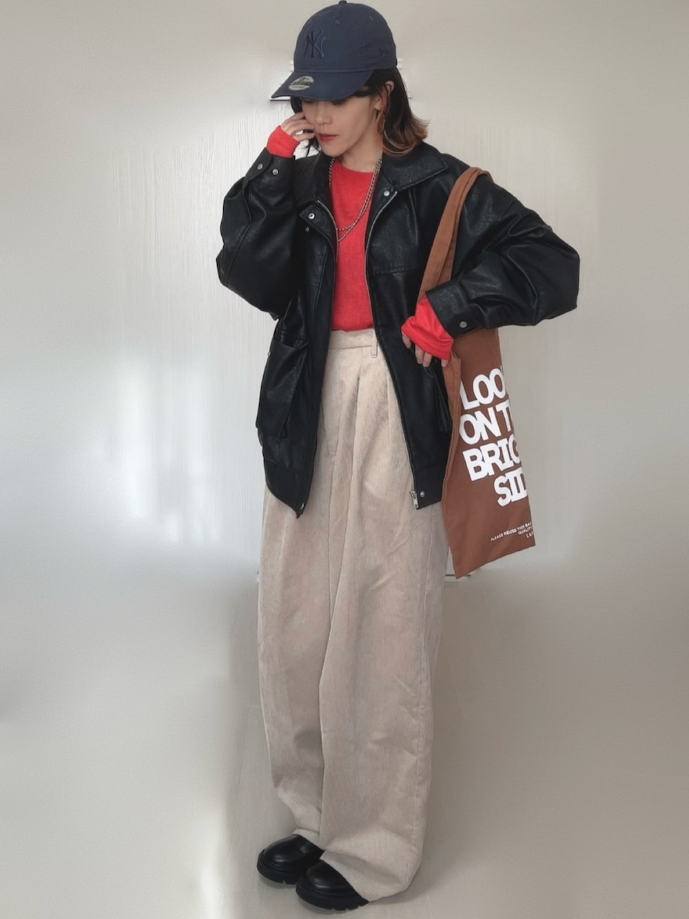 ブラック系のブルゾン、レッド系のTシャツ/カットソー、ブラック系のブーツを着用したレディースの冬コーディネートの2枚目の写真