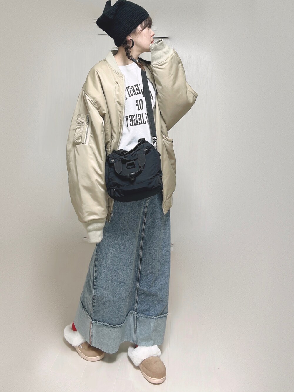 ベージュ系のMA-1、ホワイト系のスウェット、ブラック系のショルダーバッグを着用したレディースの冬コーディネートの2枚目の写真