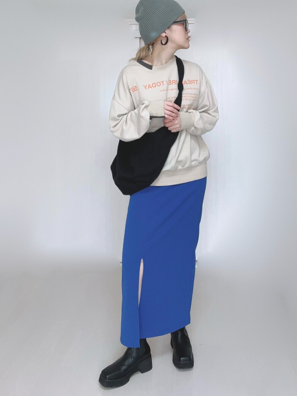 ベージュ系のスウェット、ブルー系のスカート、ブラック系のブーツを着用したレディースの冬コーディネートの2枚目の写真