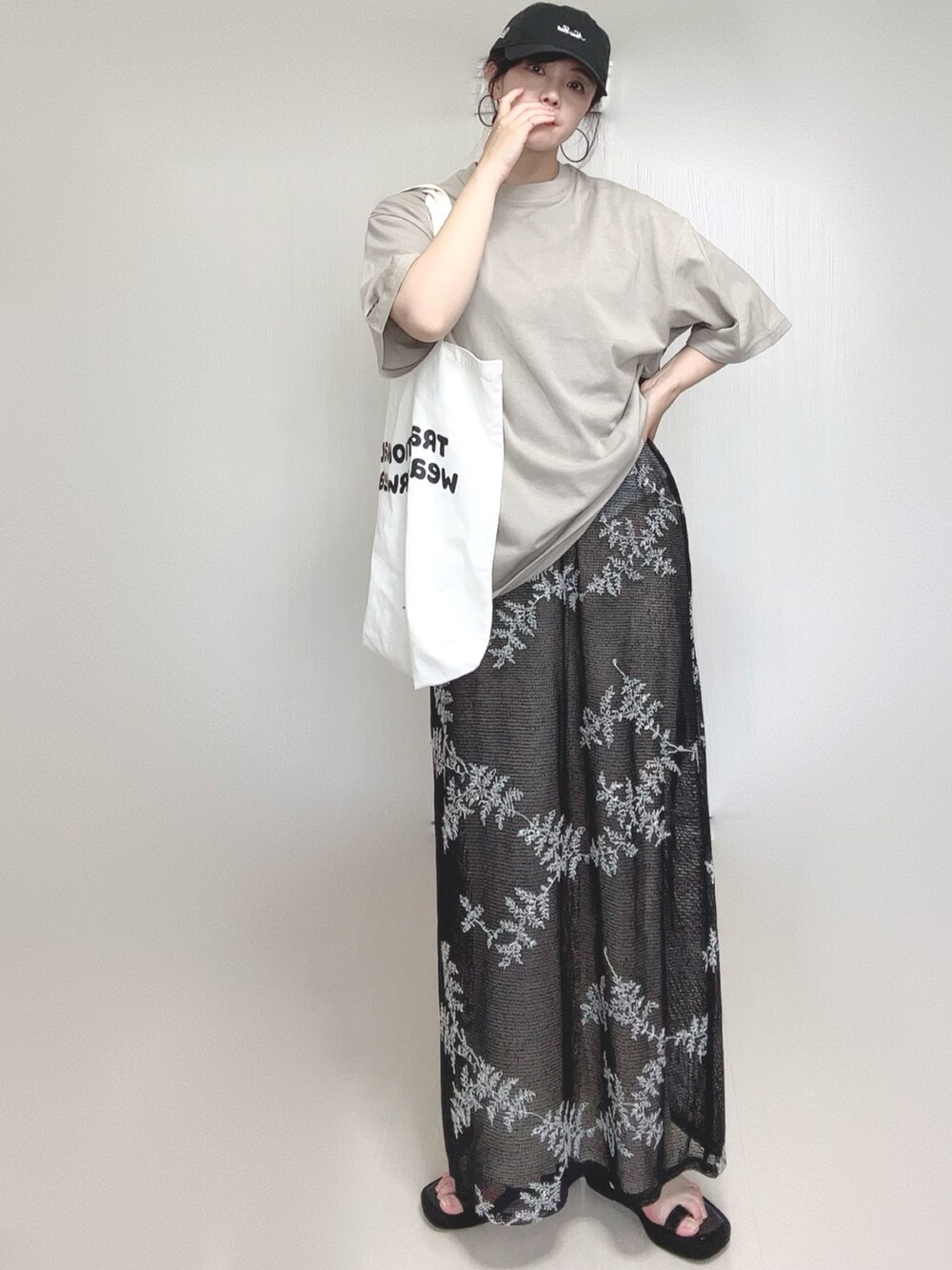 ブラック系のワンピース、ブラック系のサンダル、ベージュ系のTシャツ/カットソーを着用したレディースの夏コーディネートの2枚目の写真