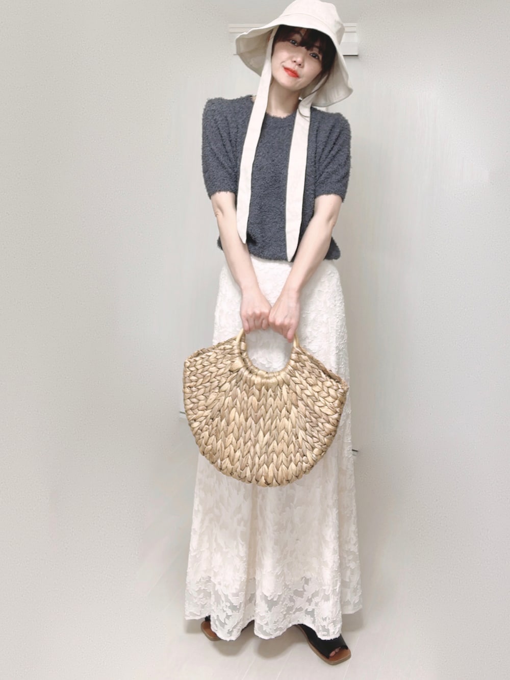 グレー系のニット/セーター、ホワイト系のスカート、ベージュ系のかごバッグを着用したレディースの夏コーディネートの4枚目の写真