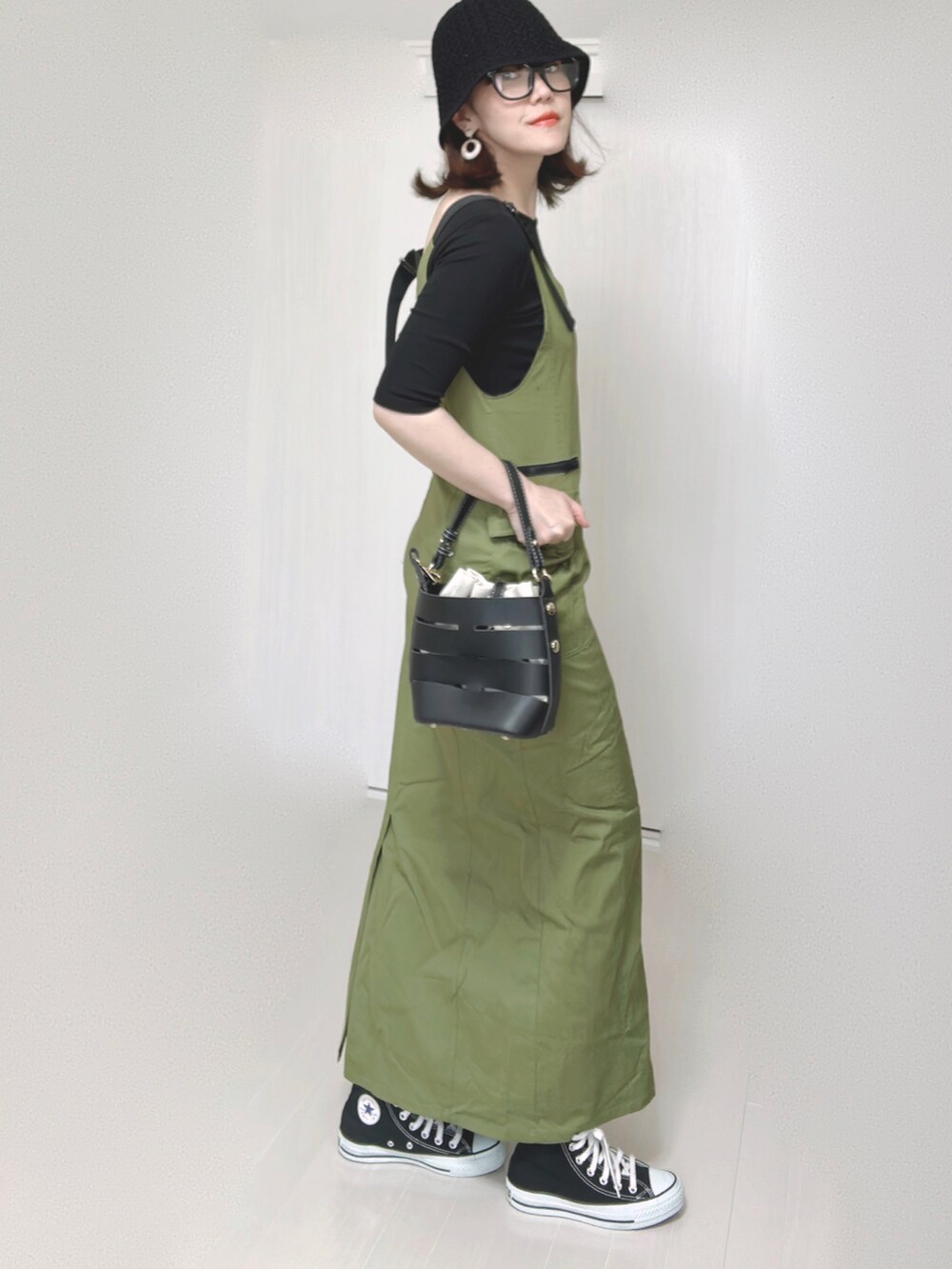 グリーン系のジャンパースカート、ブラック系のTシャツ/カットソー、ブラック系のショルダーバッグを着用したレディースの夏コーディネートの2枚目の写真