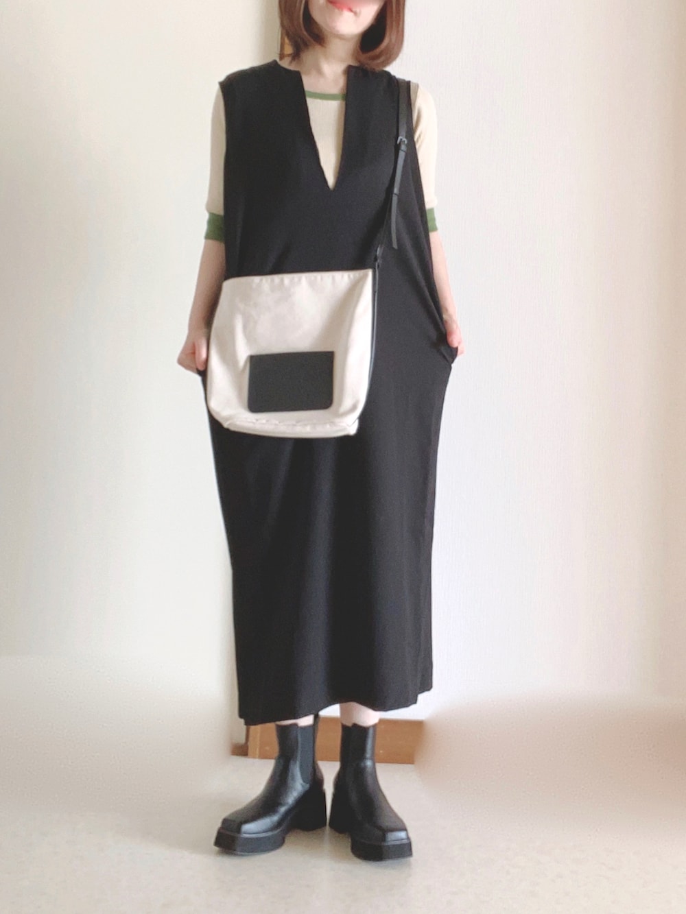 ホワイト系のショルダーバッグ、ブラック系のワンピース、ブラック系のブーツを着用したレディースの秋コーディネートの2枚目の写真