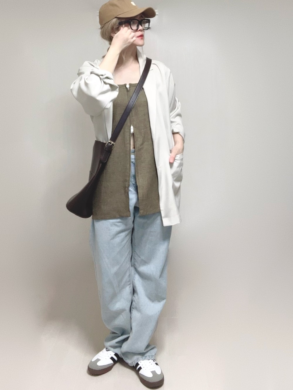 ホワイト系のテーラードジャケット、ブラウン系のベスト、ブルー系のデニムパンツを着用したレディースの春コーディネートの4枚目の写真