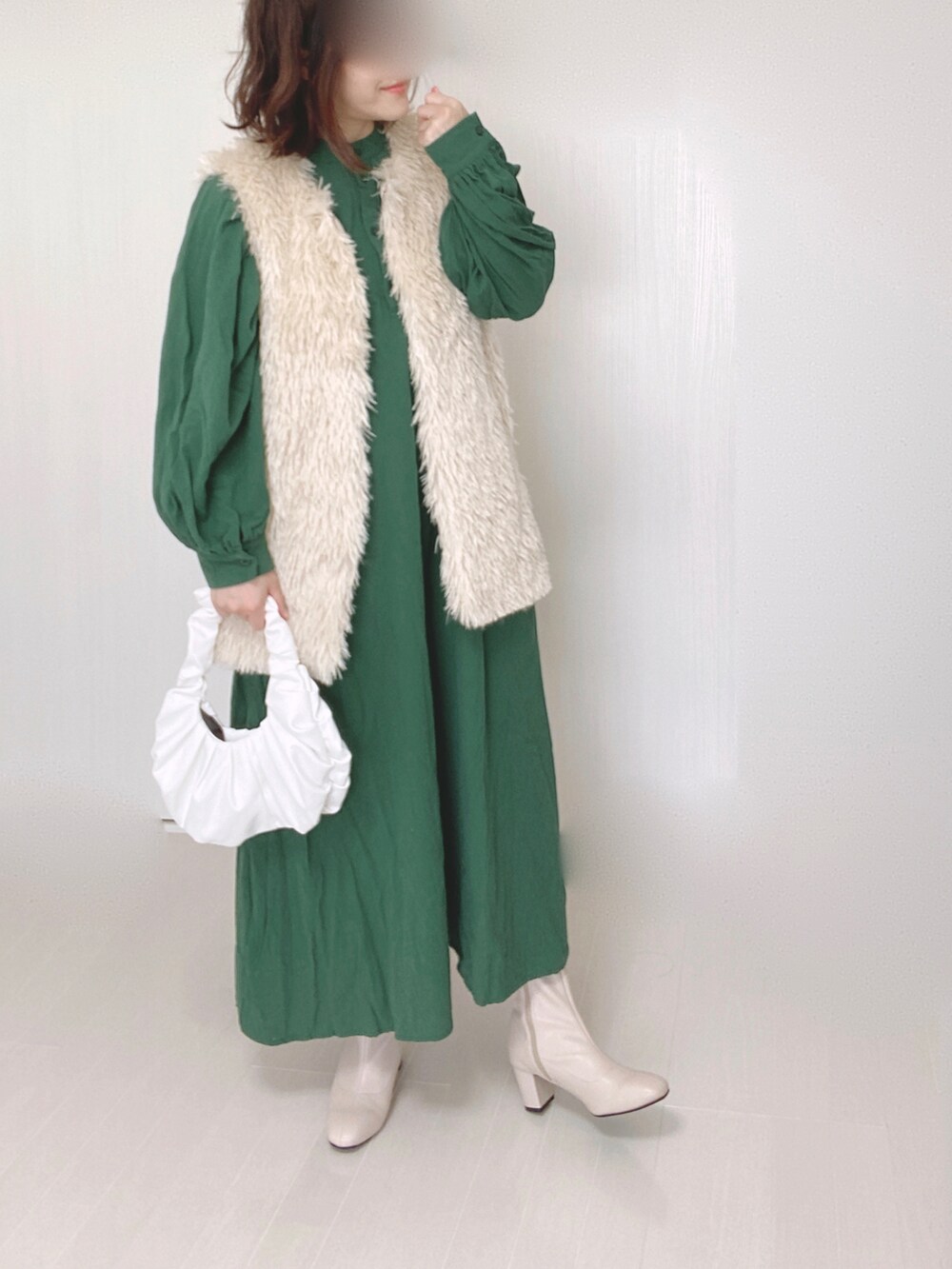ホワイト系のベスト、グリーン系のワンピース、ベージュ系のブーツを着用したレディースの秋コーディネートの3枚目の写真