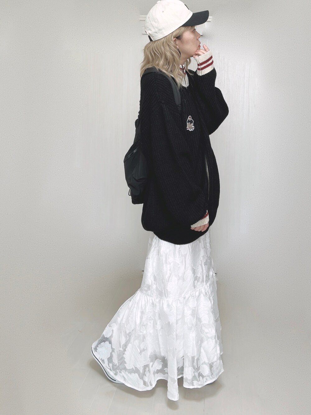 ブラック系のニット/セーター、ブラック系のバックパック/リュック、ホワイト系のスカートを着用したレディースの秋コーディネートの5枚目の写真