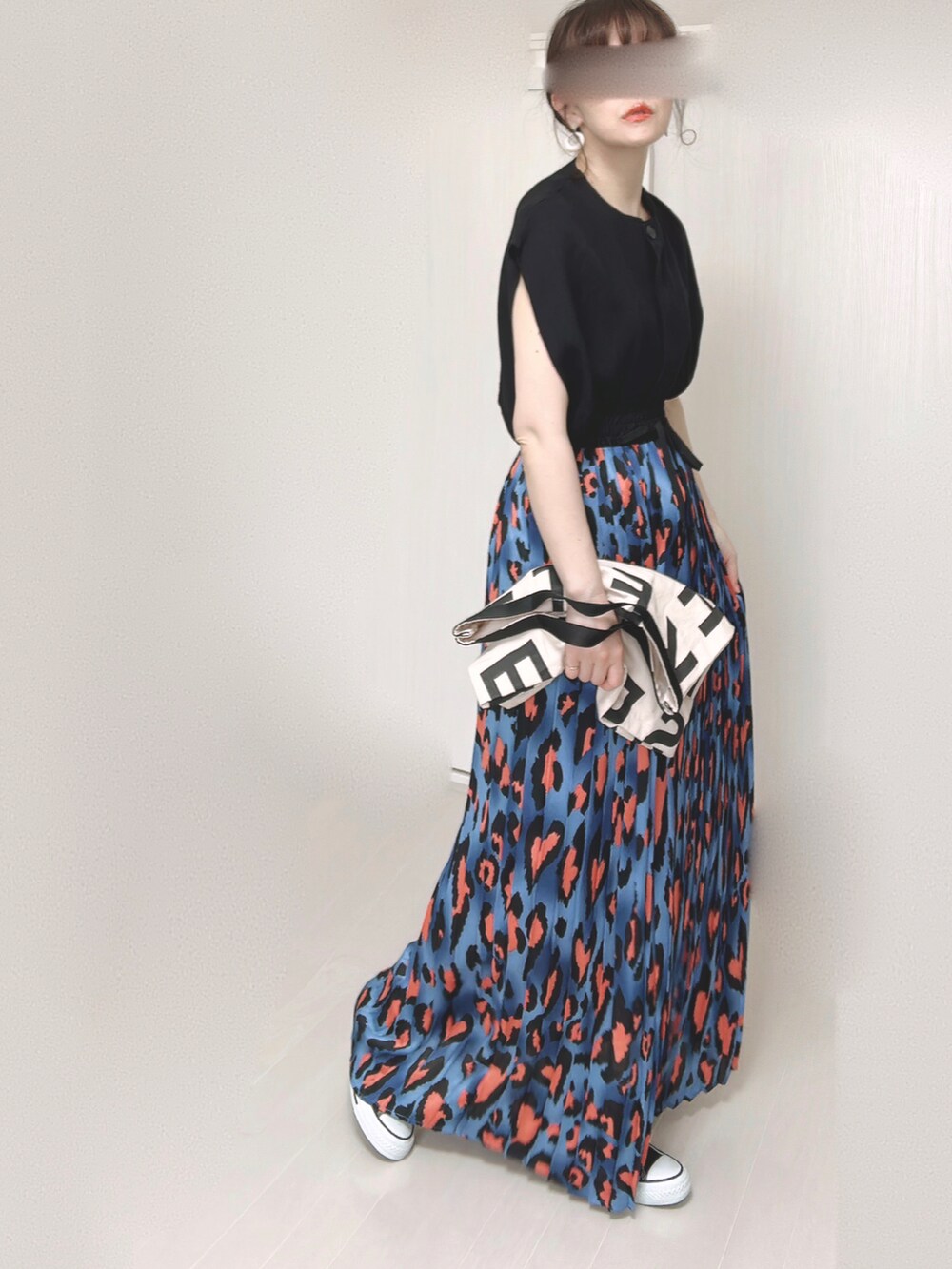 ブルー系のスカート、ブラック系のベスト、ホワイト系のトートバッグを着用したレディースの夏コーディネートの5枚目の写真