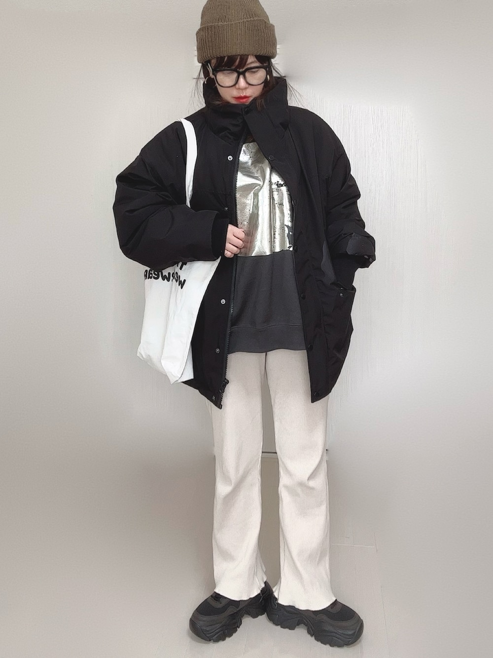 ブラック系のブルゾン、ブラック系のスウェット、ホワイト系のトートバッグを着用したレディースの冬コーディネートの4枚目の写真
