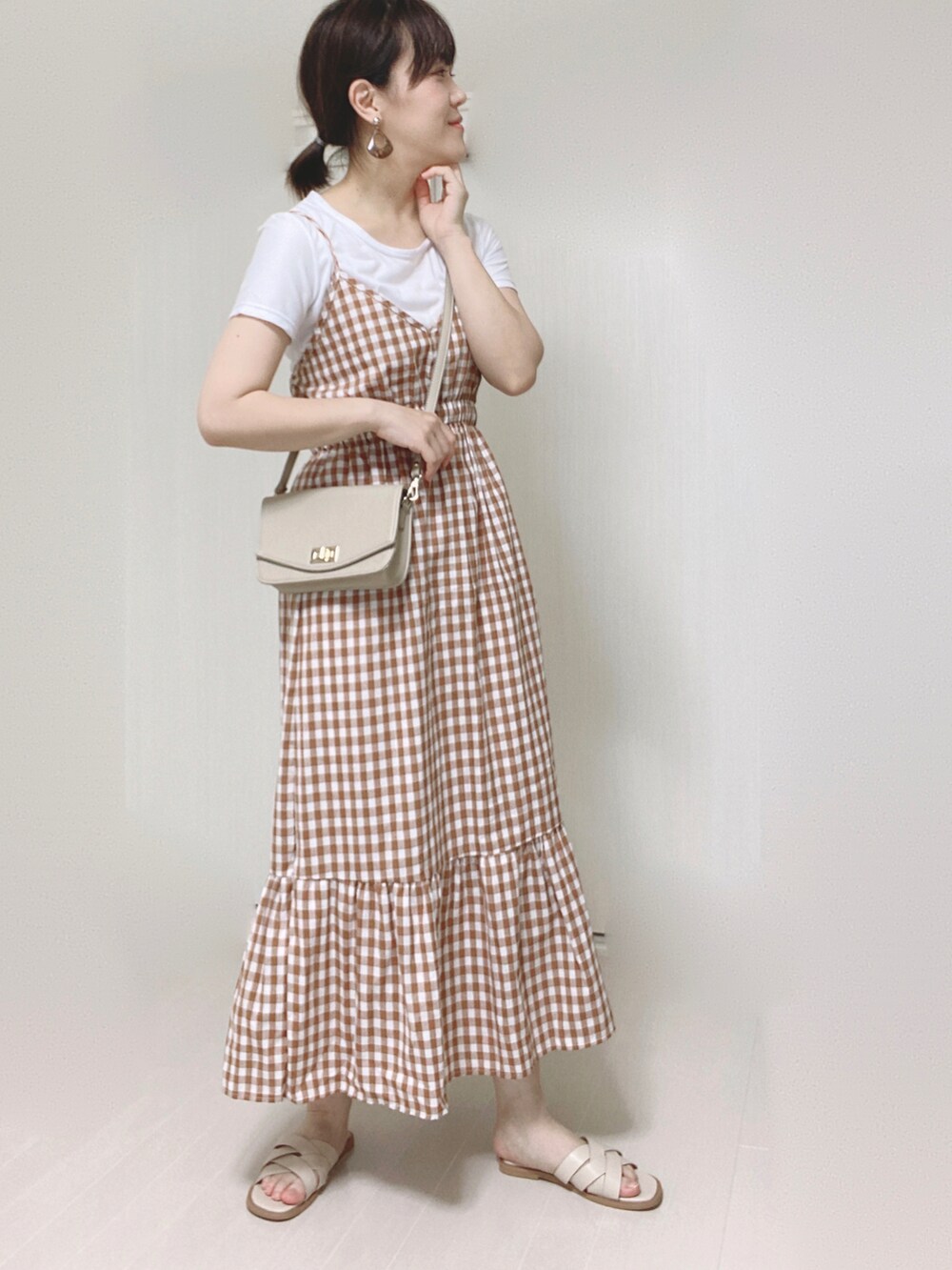 オレンジ系のワンピース、ベージュ系のショルダーバッグ、ホワイト系のサンダルを着用したレディースの夏コーディネートの2枚目の写真