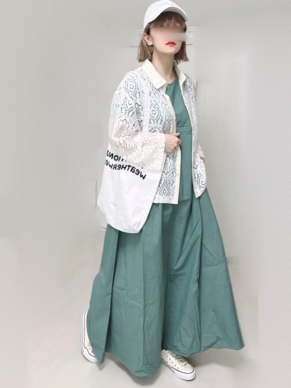 グリーン系のワンピース、ホワイト系のトートバッグ、ホワイト系のスニーカーを着用したレディースの春コーディネートの2枚目の写真