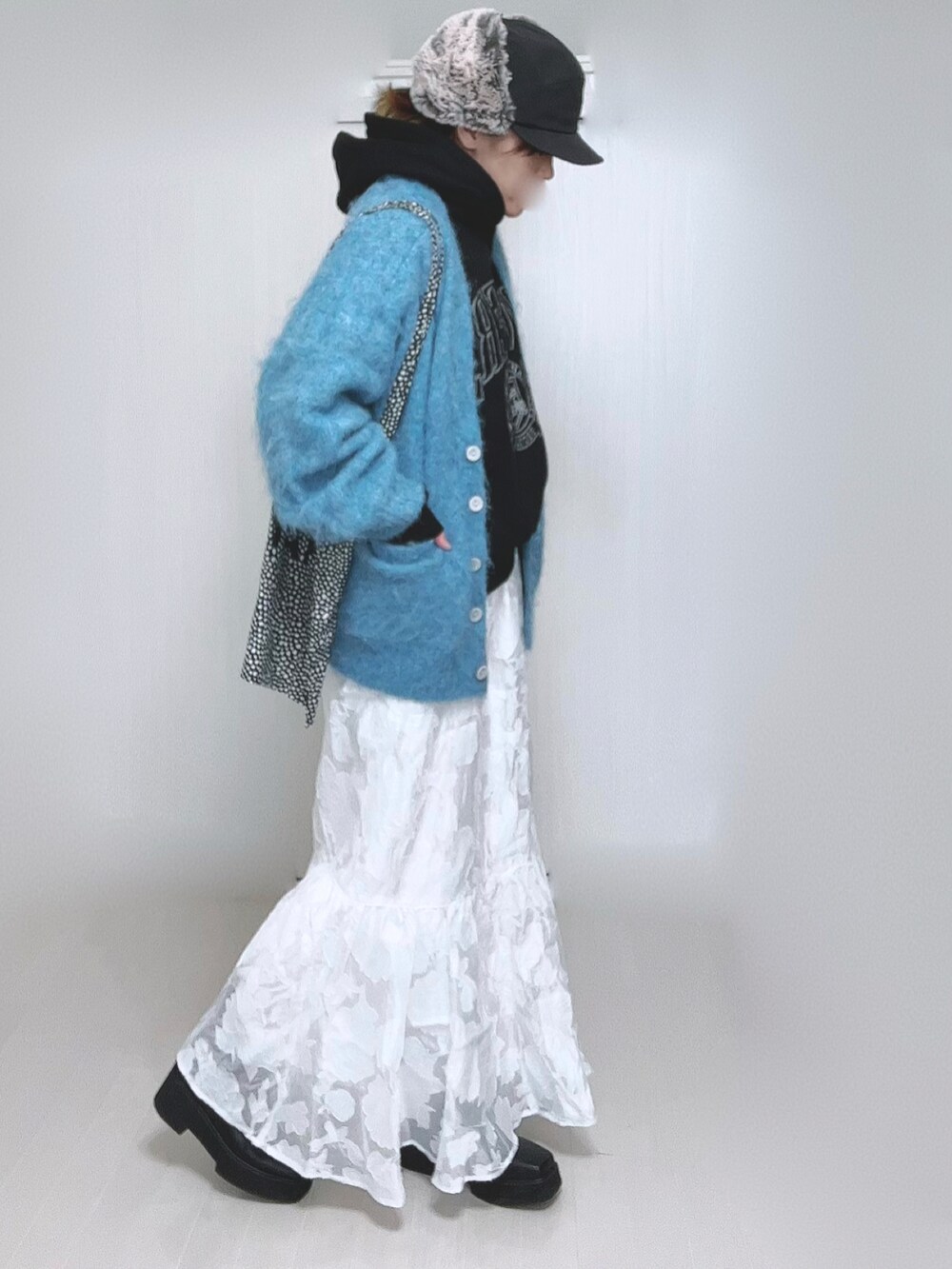 ブラック系のパーカー、ホワイト系のスカート、ブラック系のブーツを着用したレディースの冬コーディネートの2枚目の写真