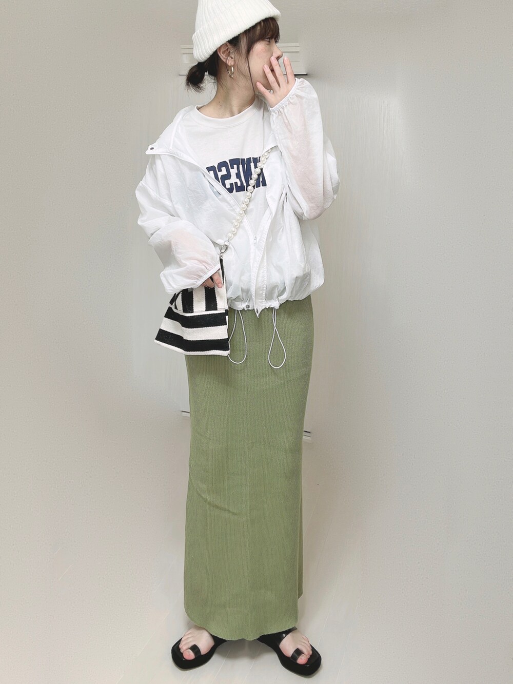 グリーン系のスカート、ホワイト系のショルダーバッグ、ブラック系のサンダルを着用したレディースの春コーディネートの5枚目の写真