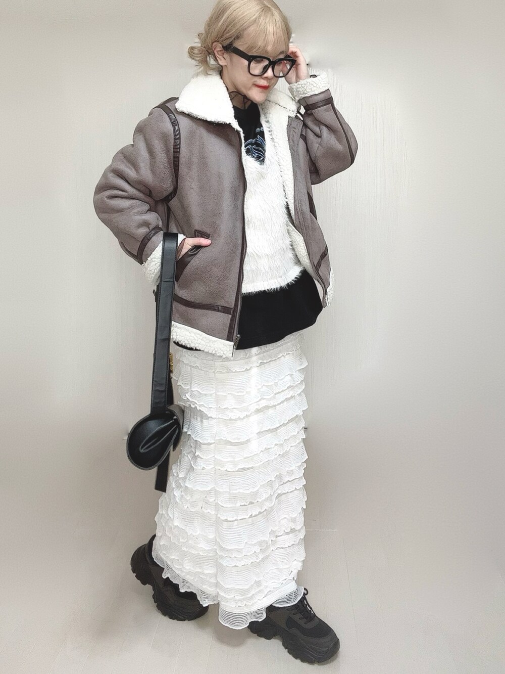 グレー系のムートンコート、ホワイト系のベスト、ブラック系のTシャツ/カットソーを着用したレディースの冬コーディネートの4枚目の写真