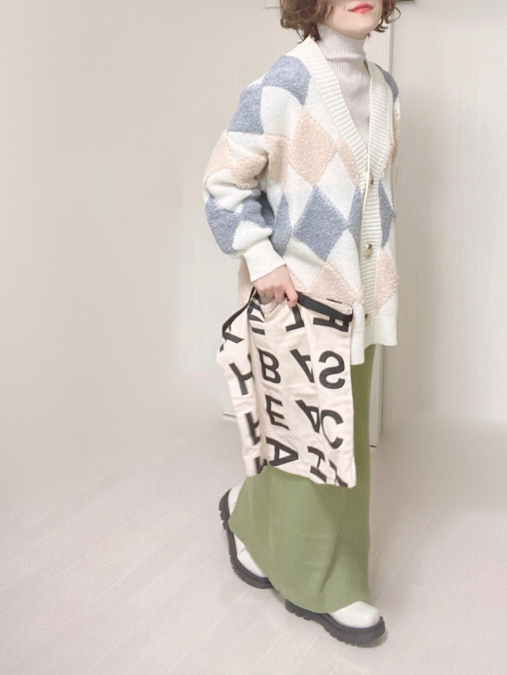 グリーン系のスカート、ホワイト系のブーツ、ホワイト系のトートバッグを着用したレディースの冬コーディネートの5枚目の写真