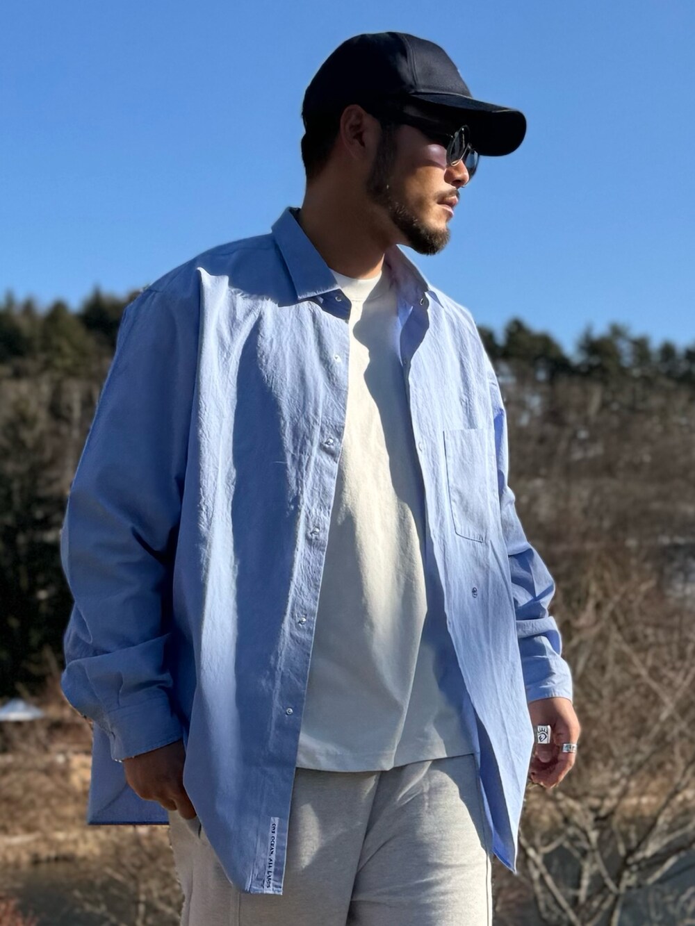 ブルー系のシャツ/ブラウス、ブルー系のキャップ、ブラック系のメガネを着用したメンズの冬コーディネートの4枚目の写真