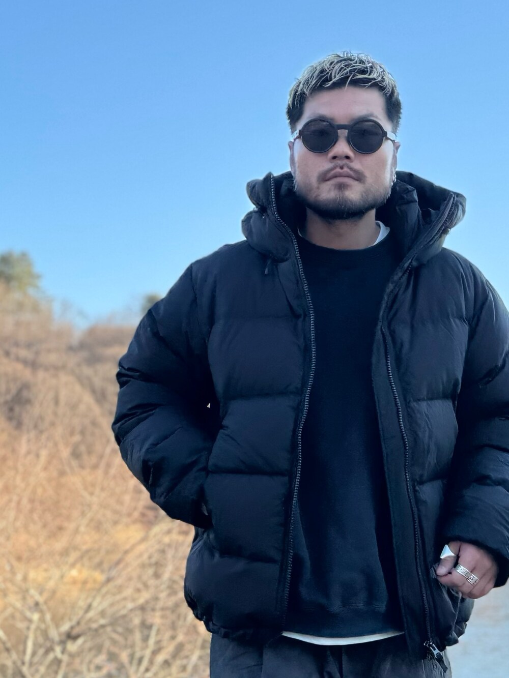 ブラック系のその他アウター、ブラック系のその他パンツ、ブラック系のメガネを着用したメンズの冬コーディネートの2枚目の写真