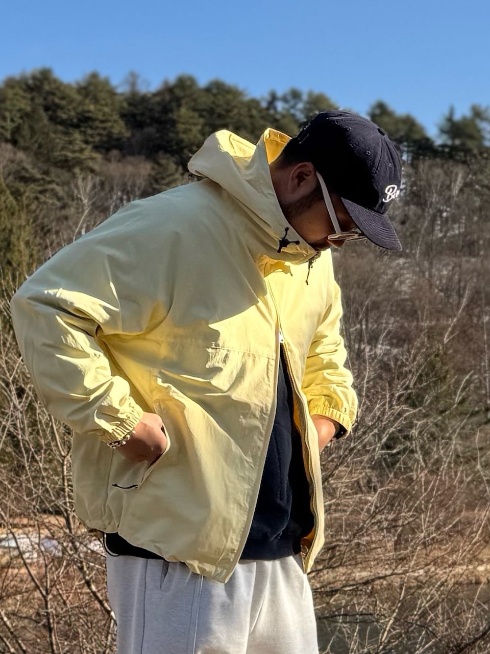 イエロー系のナイロンジャケット、ホワイト系のメガネを着用したメンズの冬コーディネートの3枚目の写真