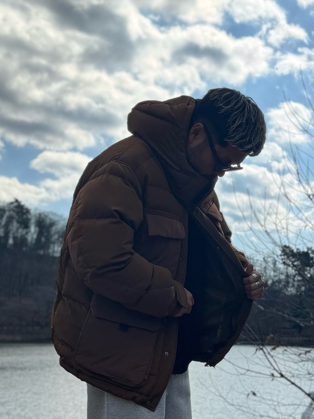 ブラウン系のその他アウター、グレー系のその他パンツ、ブラック系のメガネを着用したメンズの冬コーディネートの4枚目の写真