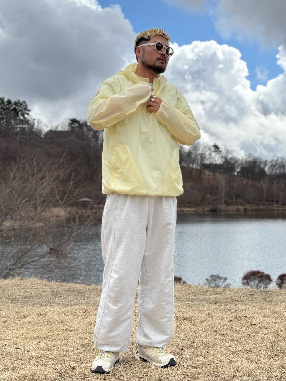 イエロー系のナイロンジャケット、ホワイト系のメガネを着用したメンズの春コーディネートの2枚目の写真
