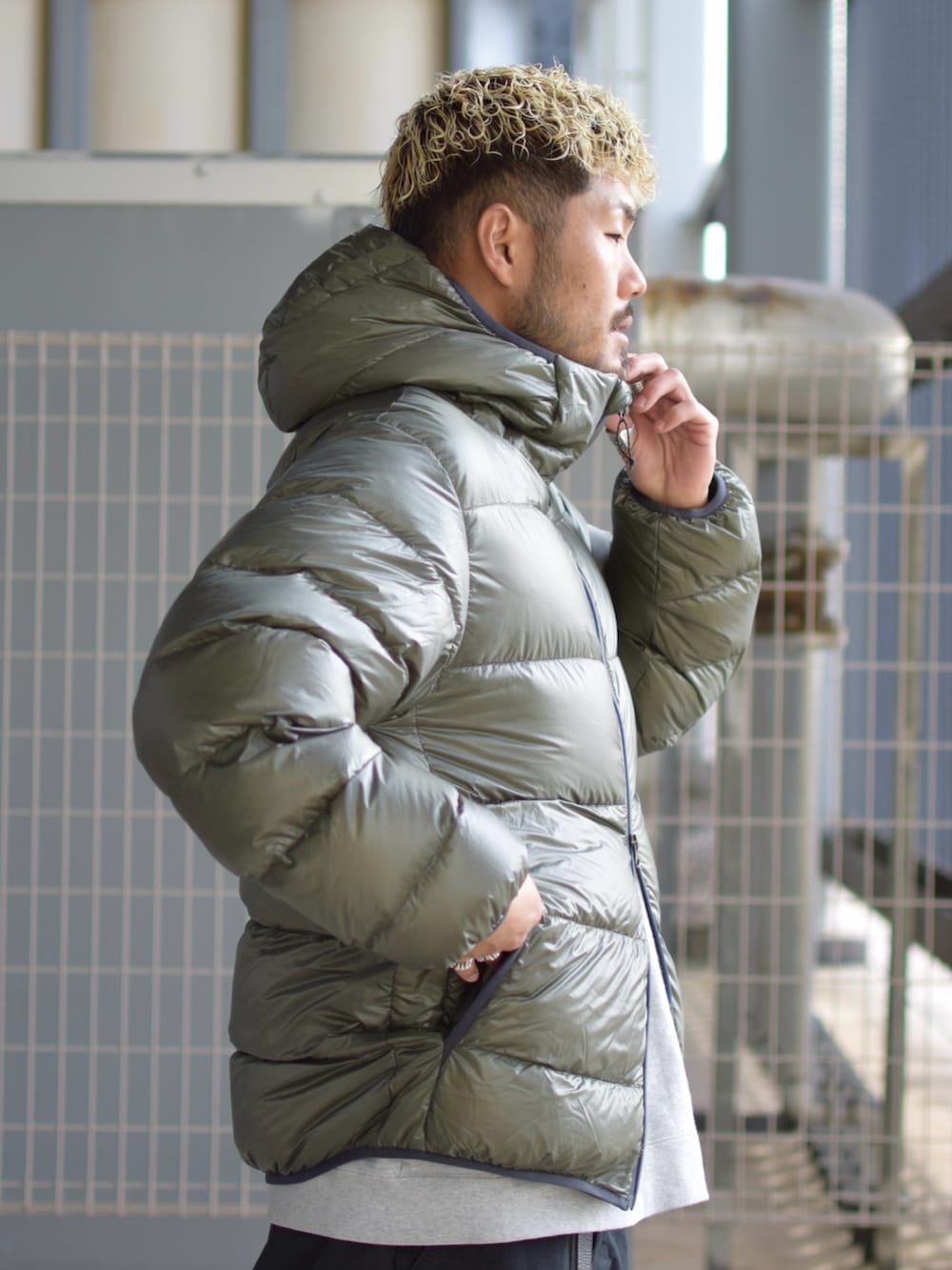 グリーン系のダウンジャケット/コート、グレー系のスウェット、ブラック系のチノパンツを着用したメンズの冬コーディネートの3枚目の写真