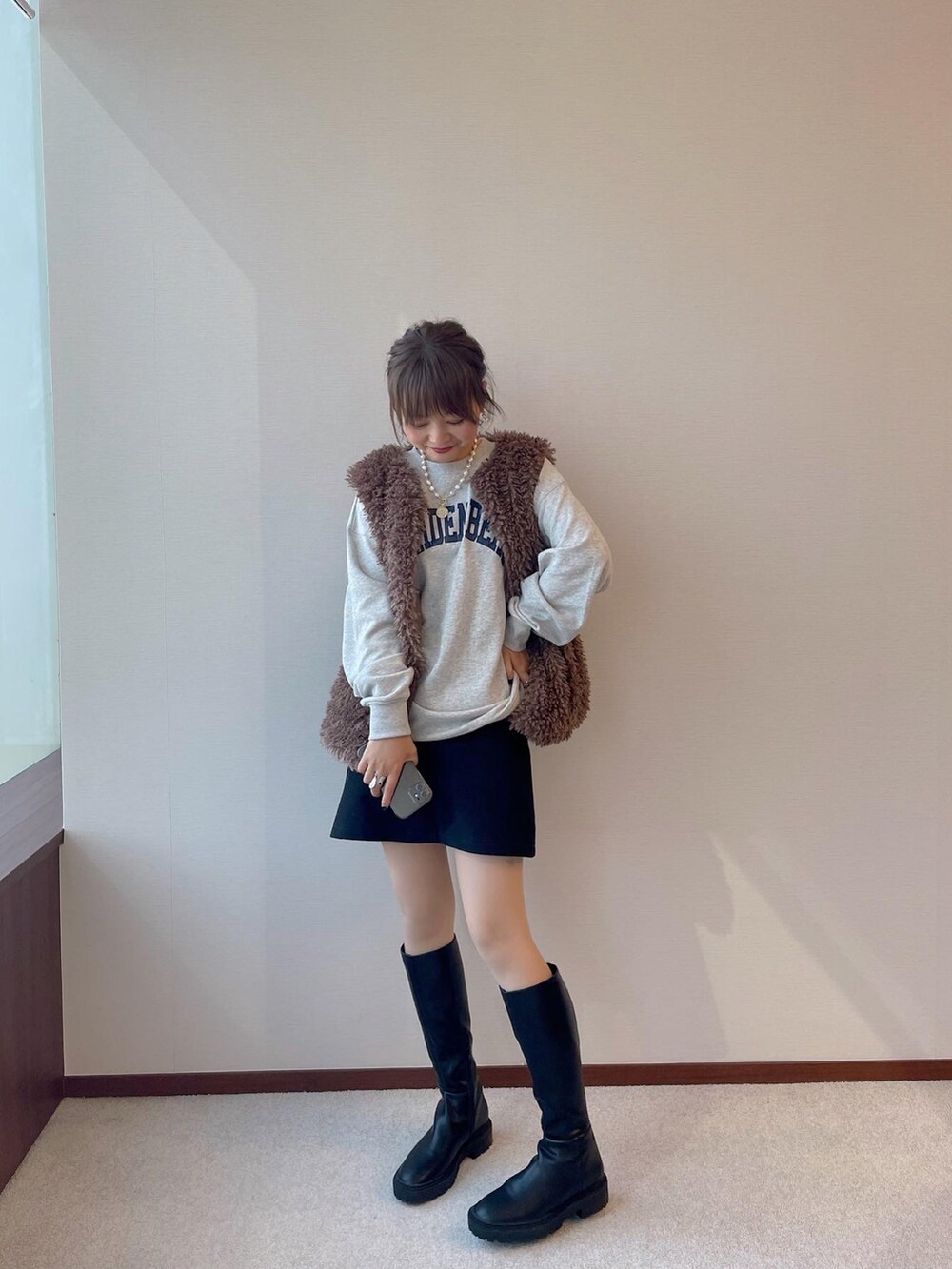 グレー系のパーカー、ブラウン系のベストを着用したレディースの冬コーディネートの2枚目の写真