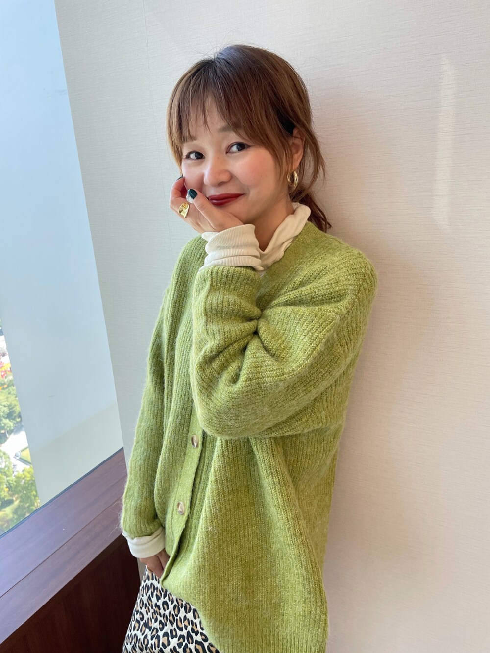 グリーン系のアンサンブル、ベージュ系のスカートを着用したレディースの冬コーディネートの2枚目の写真